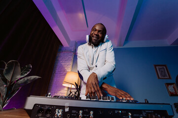 a DJ in a white suit listens to music, sings and dances. a man listens to music at a party.