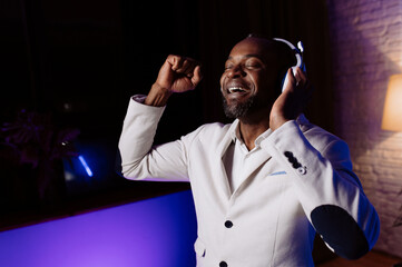 Neon light. portrait of a smiling man in headphones. Listening to music. a man in a white jacket and trousers.