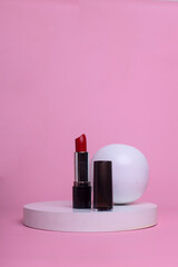 Red lipstick on the podium on a pink background.