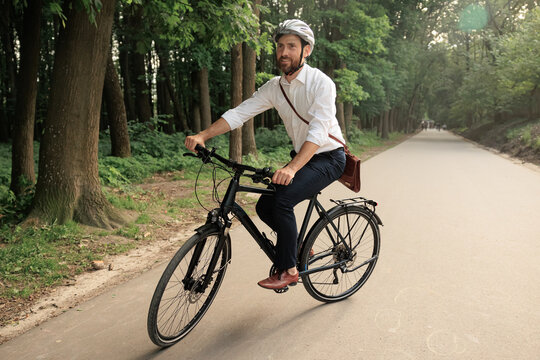 Enjoyed worker returning from job on bicycle in city park.