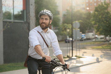 Happy bearded employee driving bicycle on street in morning.