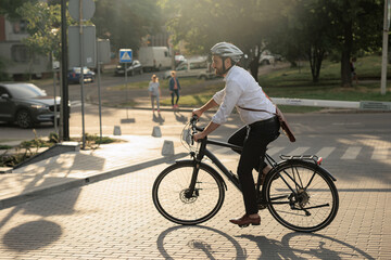 Smiling bearded entrepreneur riding on bike on street in morning.