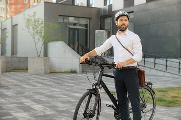 Confident handsome entrepreneur in helmet with modern bike in city.