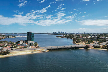 Obraz premium Aerial view of cars driving across the Mount Henry freeway bridge with the Perth city skyline in the distance.