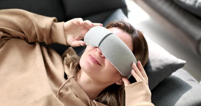 Young woman lying on sofa and putting massage glasses on her eyes 4k movie slow motion