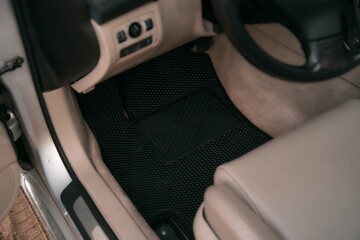 Luxury car with white leather interior with high-quality EVA floor mats in black color. Close-up of...