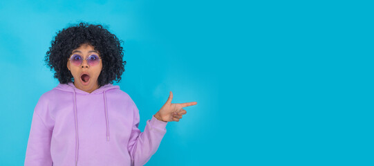 afro hair girl wearing sunglasses isolated on background with surprised expression pointing