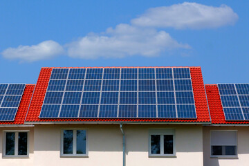 Naklejka premium roof installed photovoltaic PV sun collector solar panels. clear blue sky red clay sloped residential roof in daylight. alternative and clean energy generation. self sufficiency and off grid concept.