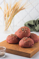 Rye and wheat flour bread buns with beetroot puree and sunflower seeds on a wooden board on a light concrete background. Baking bread with the addition of vegetable puree.
