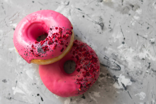 sweet donuts with strawberries and cherry pink icing on concrete background