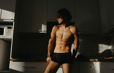 athletic slender
a man with a naked torso in the morning in the kitchen.