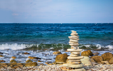 Pile stones on the beach in front of the waves