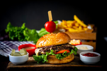 Homemade hamburger served with french fries. It looks delicious prepared with onions, hamburger patties, cheddar cheese and ham.