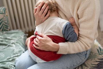 Woman with baby, mother gently hugs her child with both hands, the child sits on her lap, the baby...