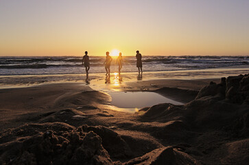 niños y sus padres corriendo hacia el mar al atardecer