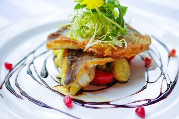 crispy fried sea bass fillet with pomegranate seeds as decor
