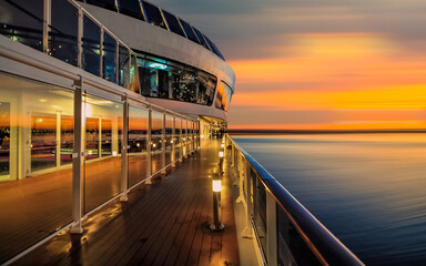 Pont promenade d'un navire de croisière en navigation avec coucher de soleil.	