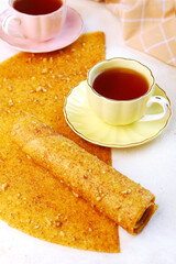 The pastille is rolled into a tube. Tea with pastille. Homemade apple pastille. Healthy food without sugar. Vertical photo.