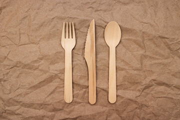 Wooden fork, spoon and knife on crumpled paper background