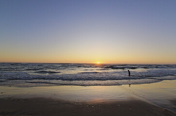 niños corriendo hacia el mar en la puesta del sol