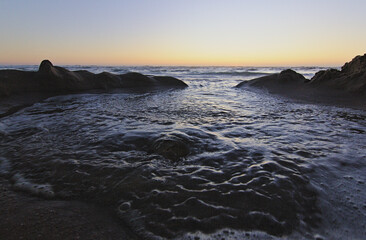 olas del mar entrando por las figuras de la arena, puesta de sol en la playa