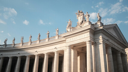 Obraz na płótnie Canvas Vatican Square Columns with Marble Statues on Top Bathed in Sunset Light, Against a Blue Sky