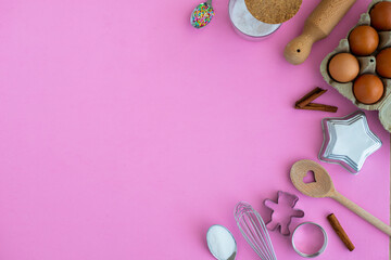 Baking tools and ingredients background with copy space. Pink wallpaper with sugar, spoons, whisk...