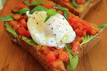 Closeup of Mouthwatering Poached Egg on Fresh Basil and Tomato Toast