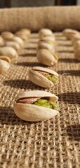 Fototapeta na wymiar Delicious pistachios on burlap fabric. Pistachio nuts close-up. Salted pistachios. Pistachios on the table. 