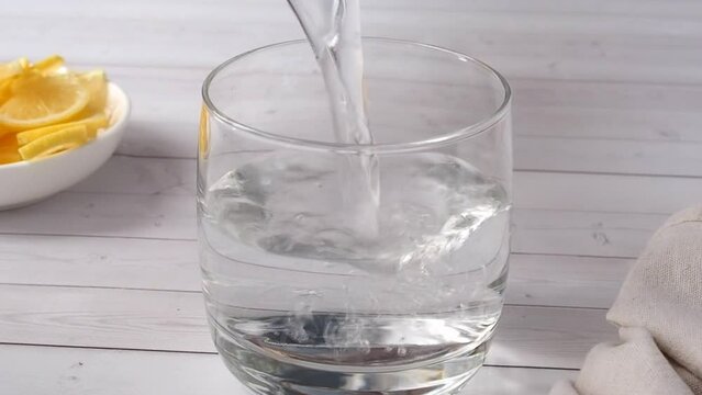 Water poured into a glass. Preparation of lemon tonic drink.