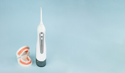 Dental prosthesis with oral cavity irrigator that cleans teeth on blue background, close-up.