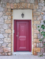 Fototapeta na wymiar A reddish painted entrance door of a classic stone wall house. Travel to Athens, Greece.