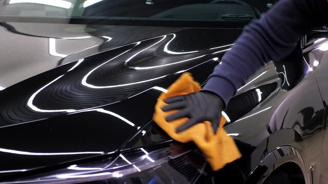 A man cleaning car with microfiber cloth, car detailing concept. Car service worker polishing car with microfiber cloth.