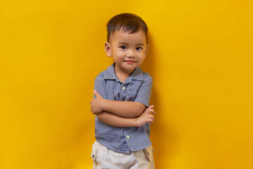 Smiling toddler Asian kid boy child wearing a shirt with crossed hands and looking happy isolated...