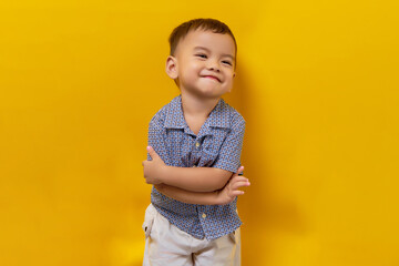 Smiling toddler Asian kid boy child wearing a shirt with crossed hands and looking happy isolated on yellow background © Bangun Stock Photo