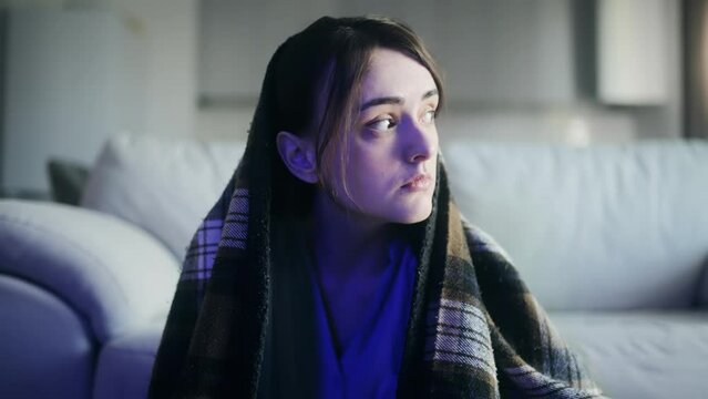 Worried young woman looking around to make sure nobody watching and eating pizza with great pleasure sitting under the blanket in the living room Break the diet or eating disorder concept