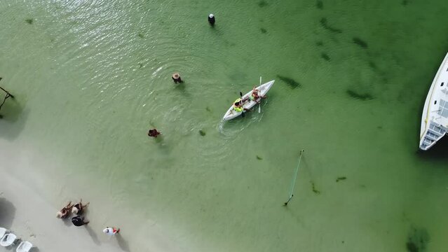 Kayaking couple in the crystal clear caribbean sea of ​​cubagua island. Margarita Island, Venezuela. Boats and catamaran anchored, atlantic ocean.