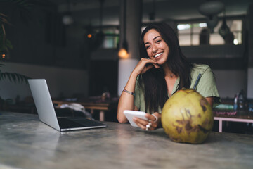 Fototapeta premium Smiling female with smartphone in cafe