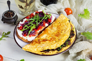 Fried omelet stuffed with mushrooms and sandwich with grilled peppers and caramelized onions