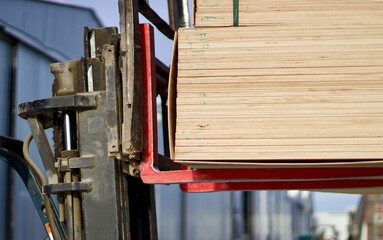 Unloading packs of plywood with a loader