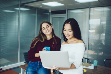 Women surfing laptop and drinking coffee during break in office
