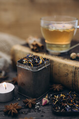 Black tea with flowers. Tea time. Photo of a black tea for a restaurant, menu or a website. Black tea with spices. Tea cup on the book. Flowers in the tea