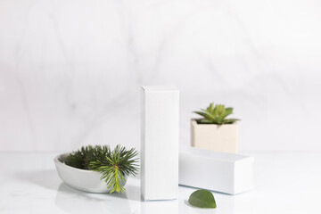 Mockup of two white boxes of cosmetic and facial care products, with green leaves