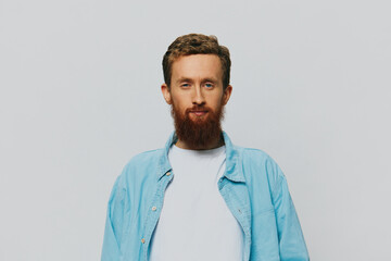 Male hipster portrait smile on gray background in blue shirt and white t-shirt, portrait of a man with a beard