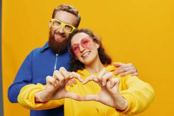 Man and woman couple smiling cheerfully and crooked with glasses, on yellow background, symbols...