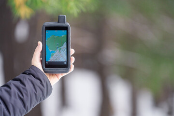 Tourist navigator in a shockproof rubberized case in a man's hand on a blurry background of a...