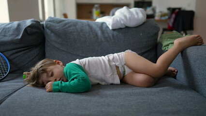 Obraz premium Funny little boy laying on sofa sleeping during afternoon nap. Baby toddler wearing diapers asleep on couch