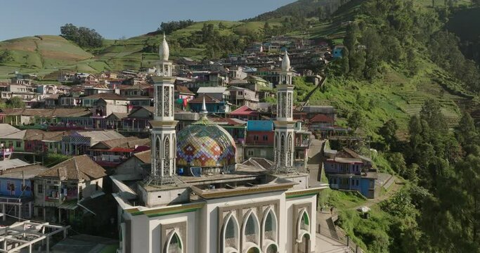 Aerial Shot Of Masjid Baituttaqwa Butuh In Mini Village, Drone Flying Forward Over Houses On Sunny Day - Java, Indonesia