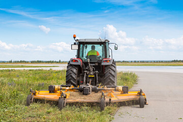 Wheel tractor with lawn mower by the road © Dushlik