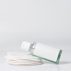 A bottle of facial cleanser rests on reusable sponges